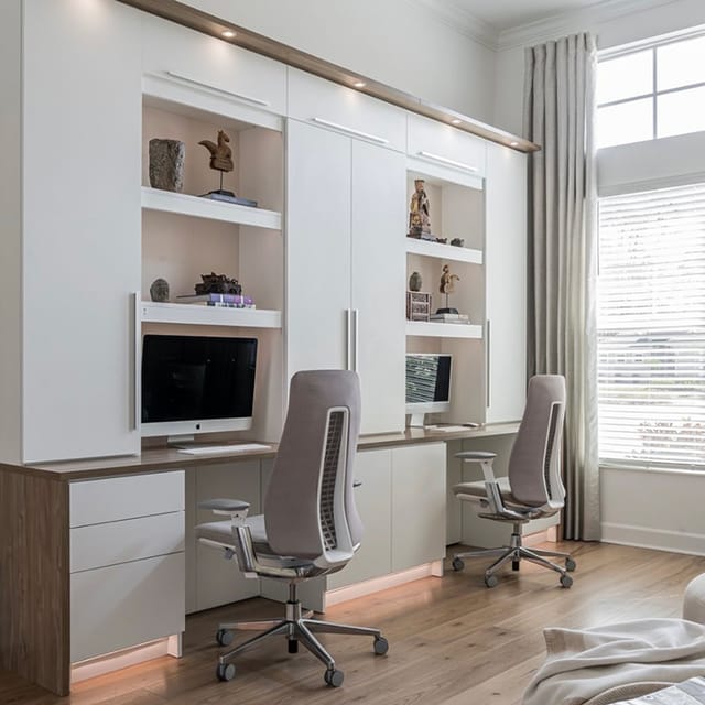 Home office workspace designed with custom shelving and two work desks storage drawers by California Closets